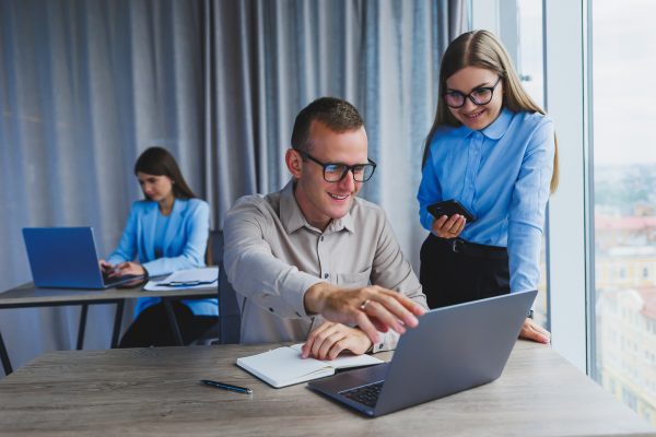 Businessman and female colleague working in modern office at laptop. Colleagues in the office